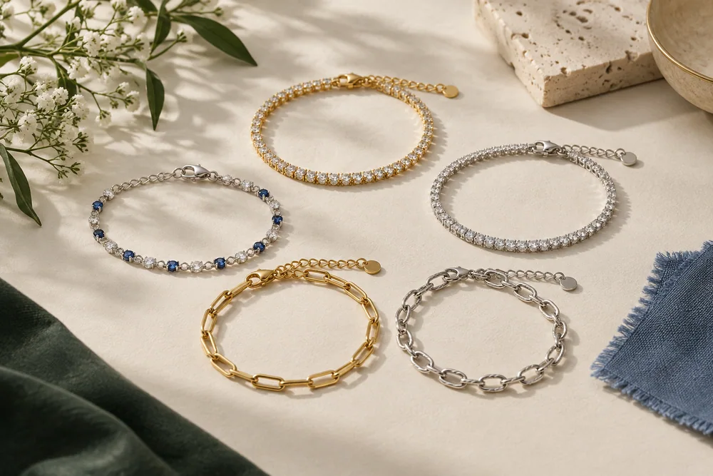 An editorial still life of crystal-line and chain bracelet ideas with blue and green fabric accents.