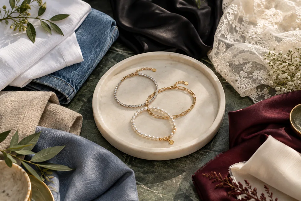 Bracelet styling ideas on a tray beside denim, satin, lace and linen textures.
